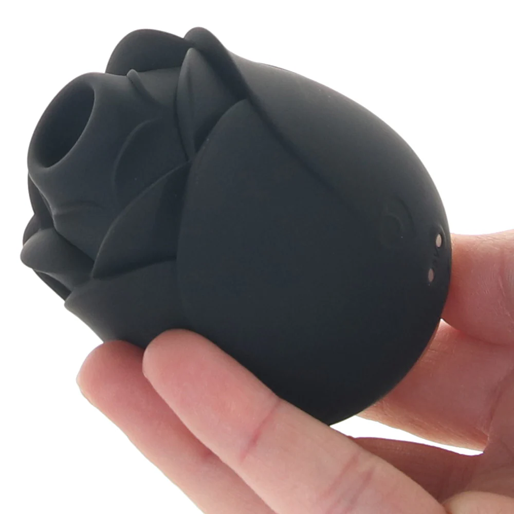 A black, rose-shaped vibrator being held in a person's hand.